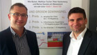 Herr Embach (links) und Herr Hartmayer (rechts) in den Produktionsräumen in Braunschweig vor einem Plakat der EAB Solar mit einer Einladung zu einer Autogrammstunde